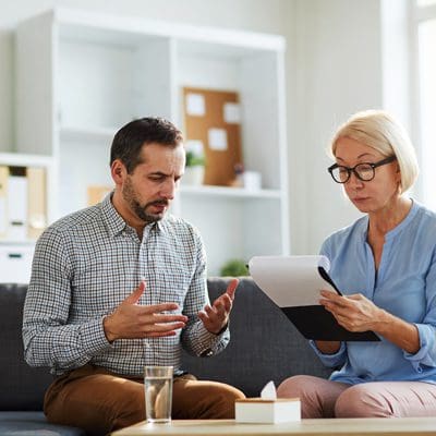 man explaining himself to his female therapist in office