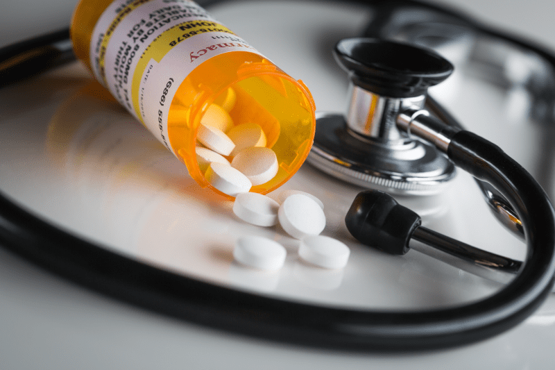 Pills spilling from bottle on table - drugs