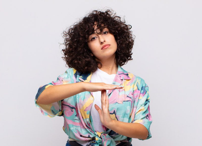 beautiful young woman with dark curly hair making the "time out" hand signal - anger