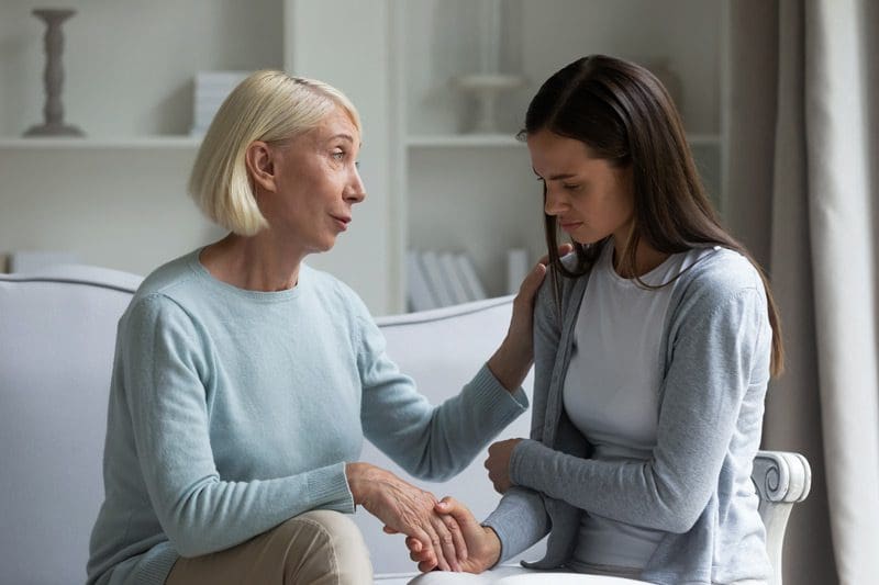 mother comforting upset young adult daughter - family support