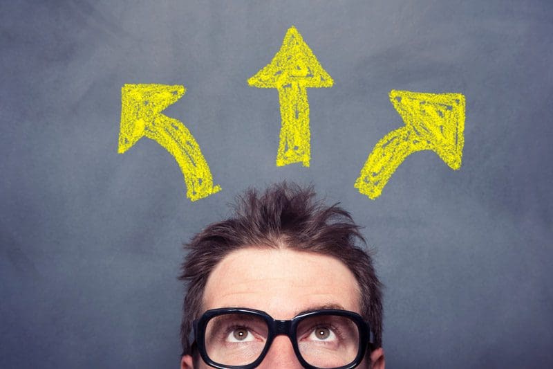 cropped shot of man in glasses looking up against a chalkboard background with three yellow arrows pointing in different upward directions - rehab