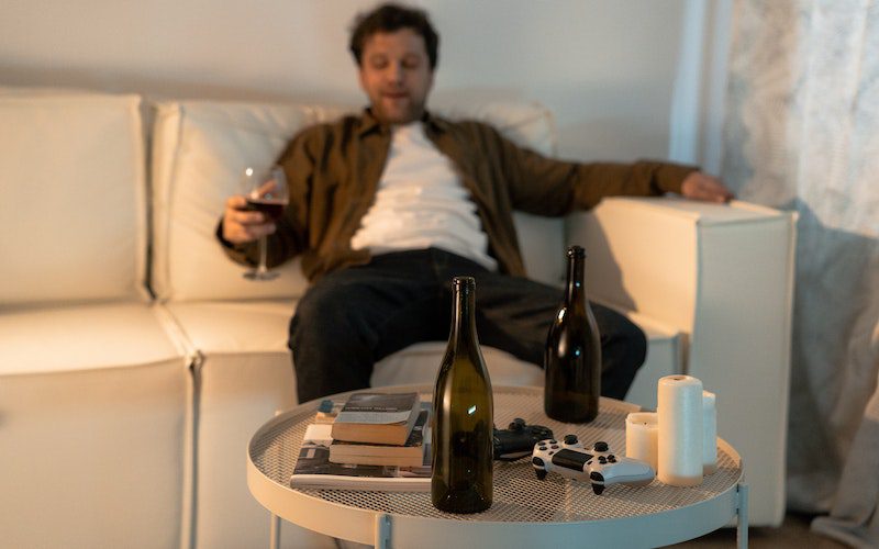 man sitting on couch drinking wine alcohol relapse